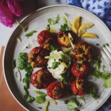 Vegan stuffed hot cherry peppers with vegan yogurt on a white ceramic plate.