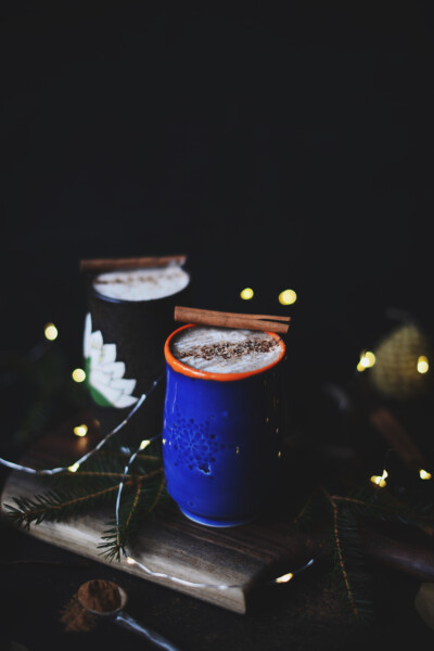 Two ceramic tumblers of vegan Irish moss eggnog garnished with cinnamon sticks.