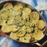 Vegan potato and kale gratin in an oval casserole dish with brass handles.