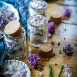 Small glass jars with cork tops filled with chive blossom finishing salt