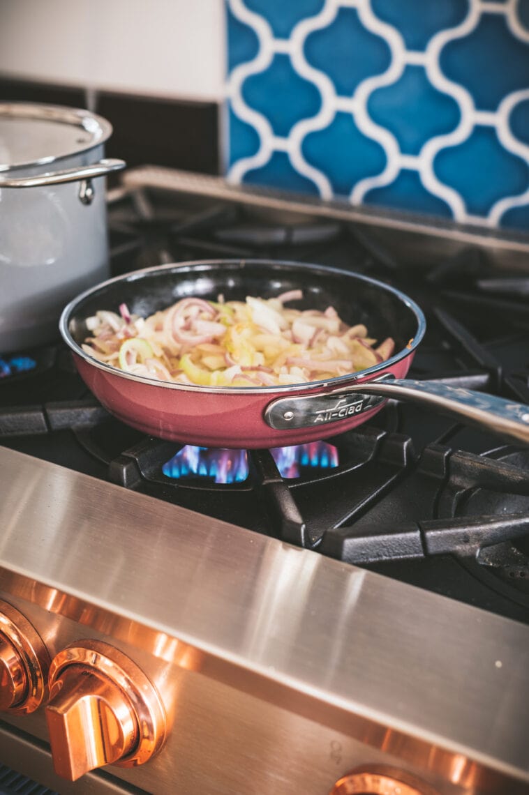 Onions are sauteeing in a a skillet on a stovetop.