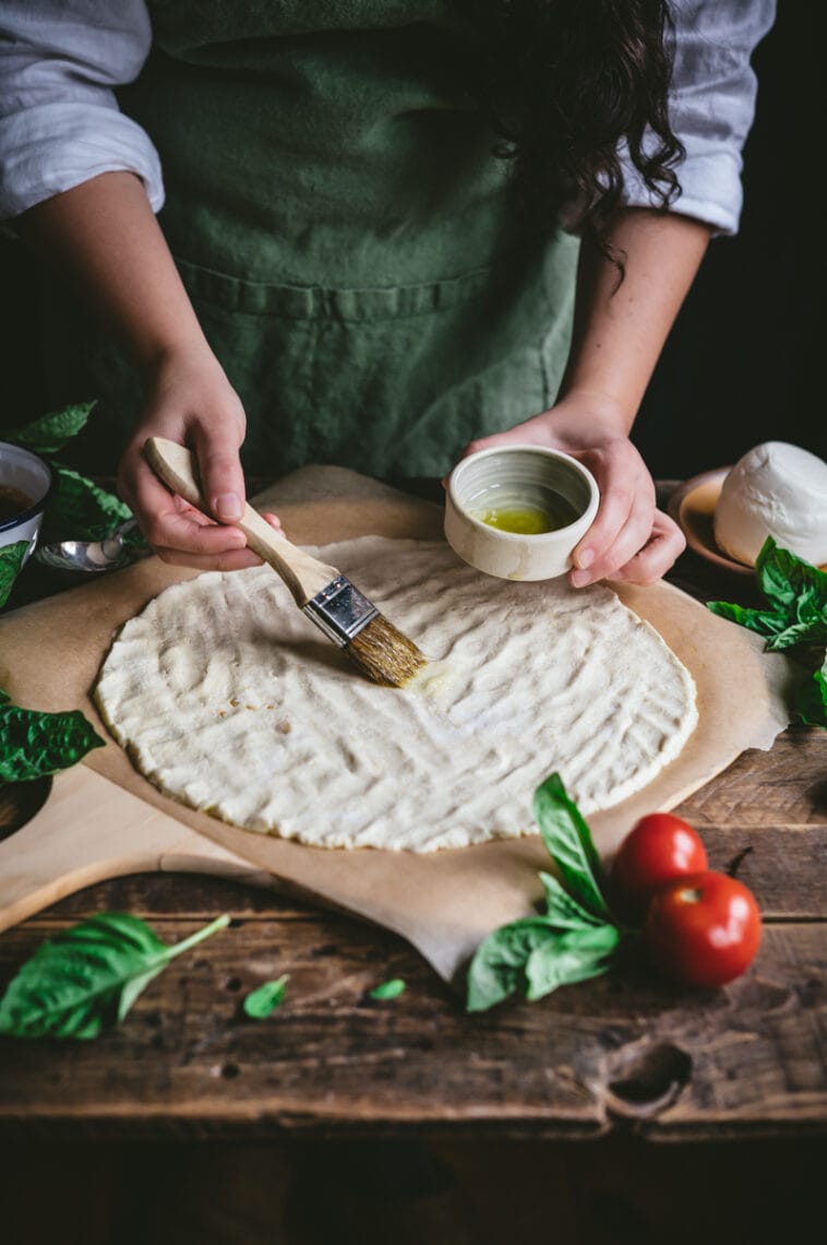 Kaity brushed olive oil over uncooked gluten-free cassava-chickpea pizza crust.