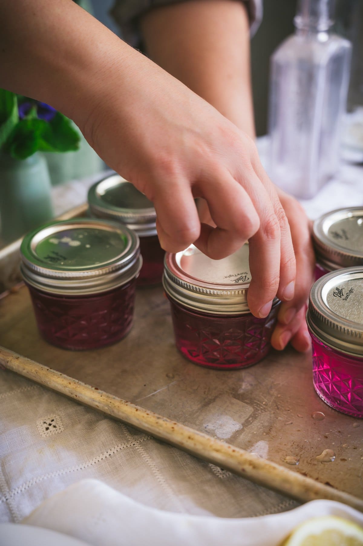 Kaity screws the ring seals to finger tight on the jars of violet jelly.