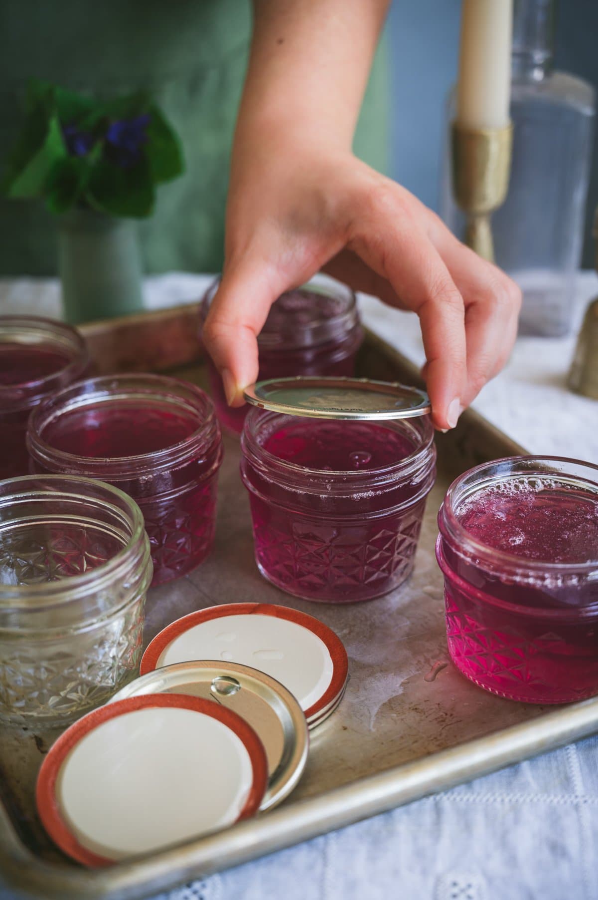 Kaity places sterilized lids onto the filled jars of wild violet jelly.