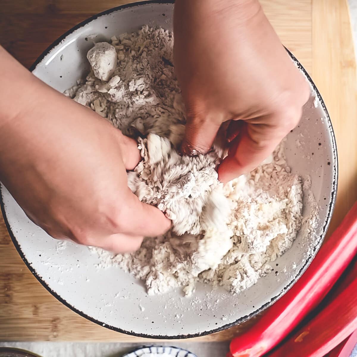 Rubbing butter into dry ingredients with fingertips to make crumble topping.