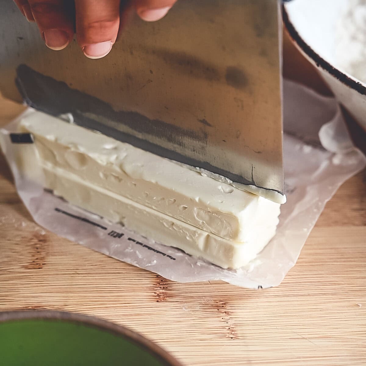 Cutting a stick of butter into small cubes with a bench knife.