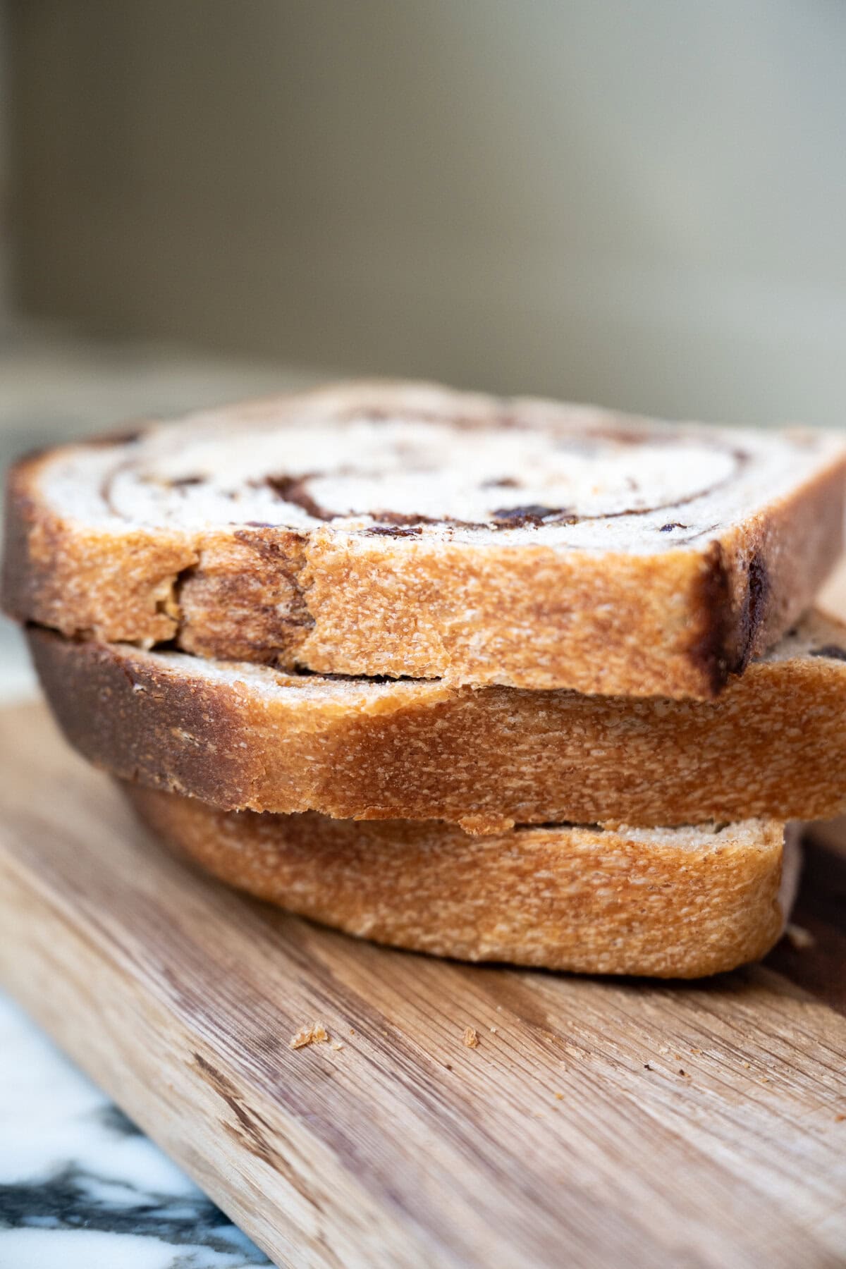 Cinnamon raisin sourdough bread slices stacked on a wooden cutting board, with a soft focus background.