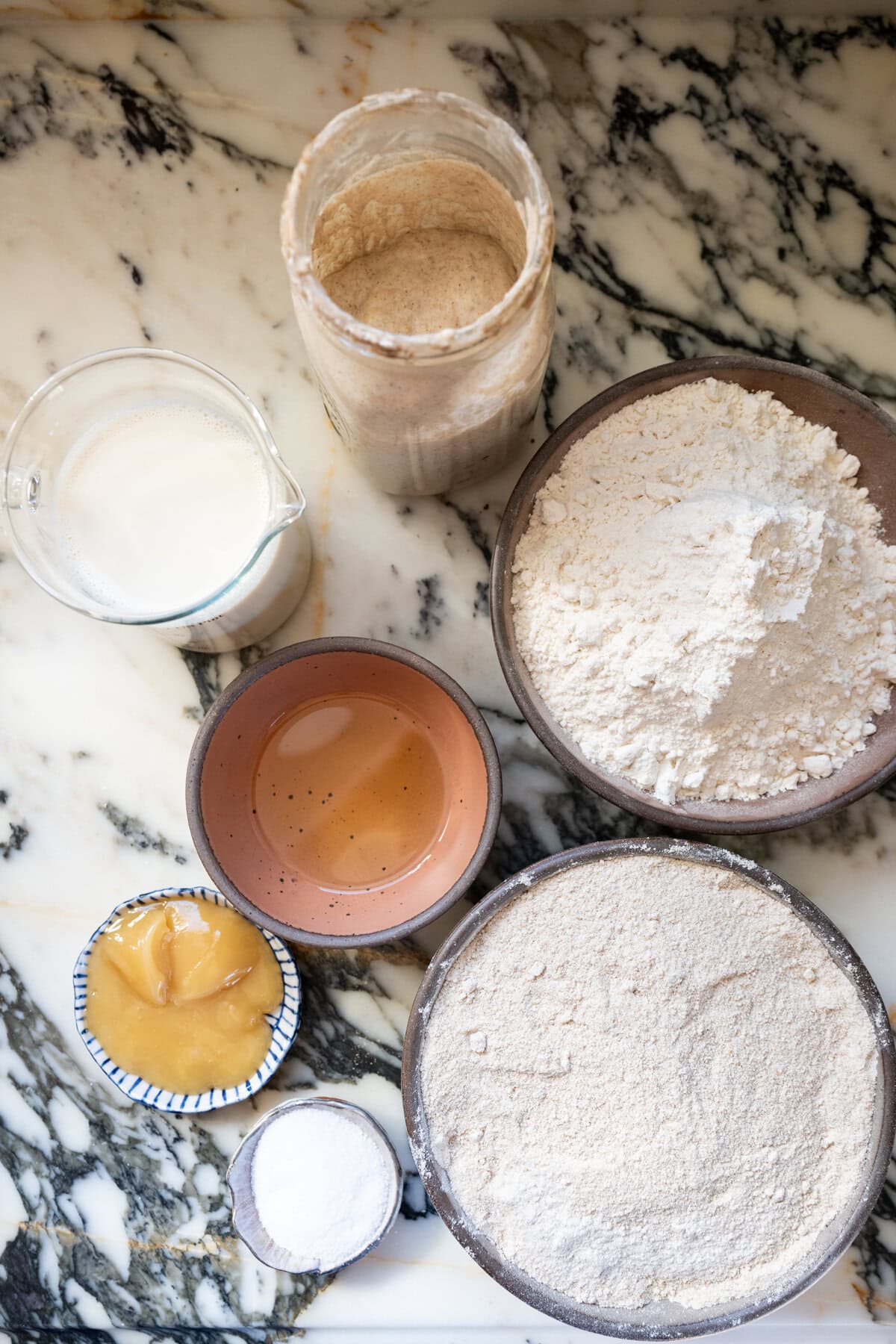 Alt text: Ingredients for whole wheat sourdough sandwich bread including bread flour, whole wheat flour, milk, honey, salt, and starter