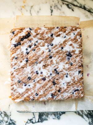 Homemade blueberry crumb cake topped with cinnamon streusel and a drizzle of lemon glaze, photographed from above.