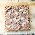 Homemade blueberry crumb cake topped with cinnamon streusel and a drizzle of lemon glaze, photographed from above.