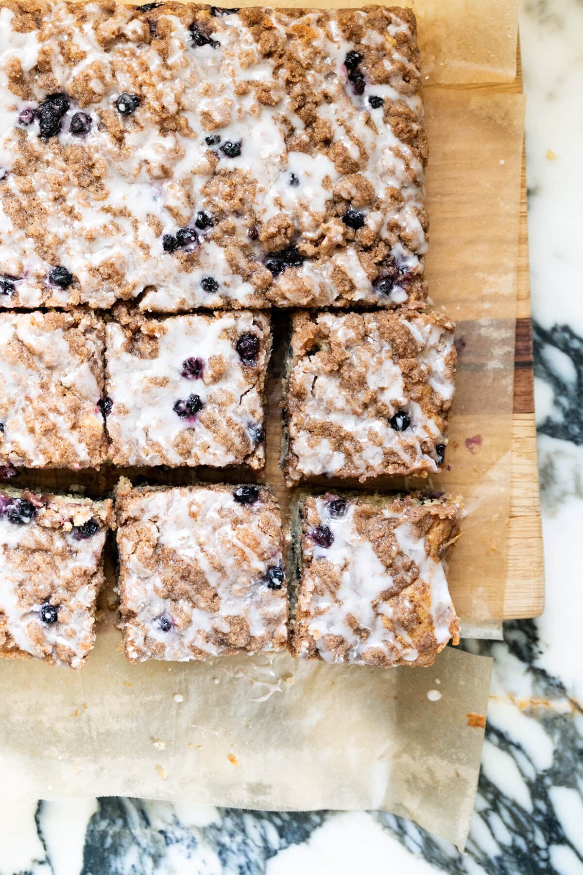 Freshly baked blueberry crumb cake sliced into squares, showing the crumbly cinnamon topping and blueberries throughout.