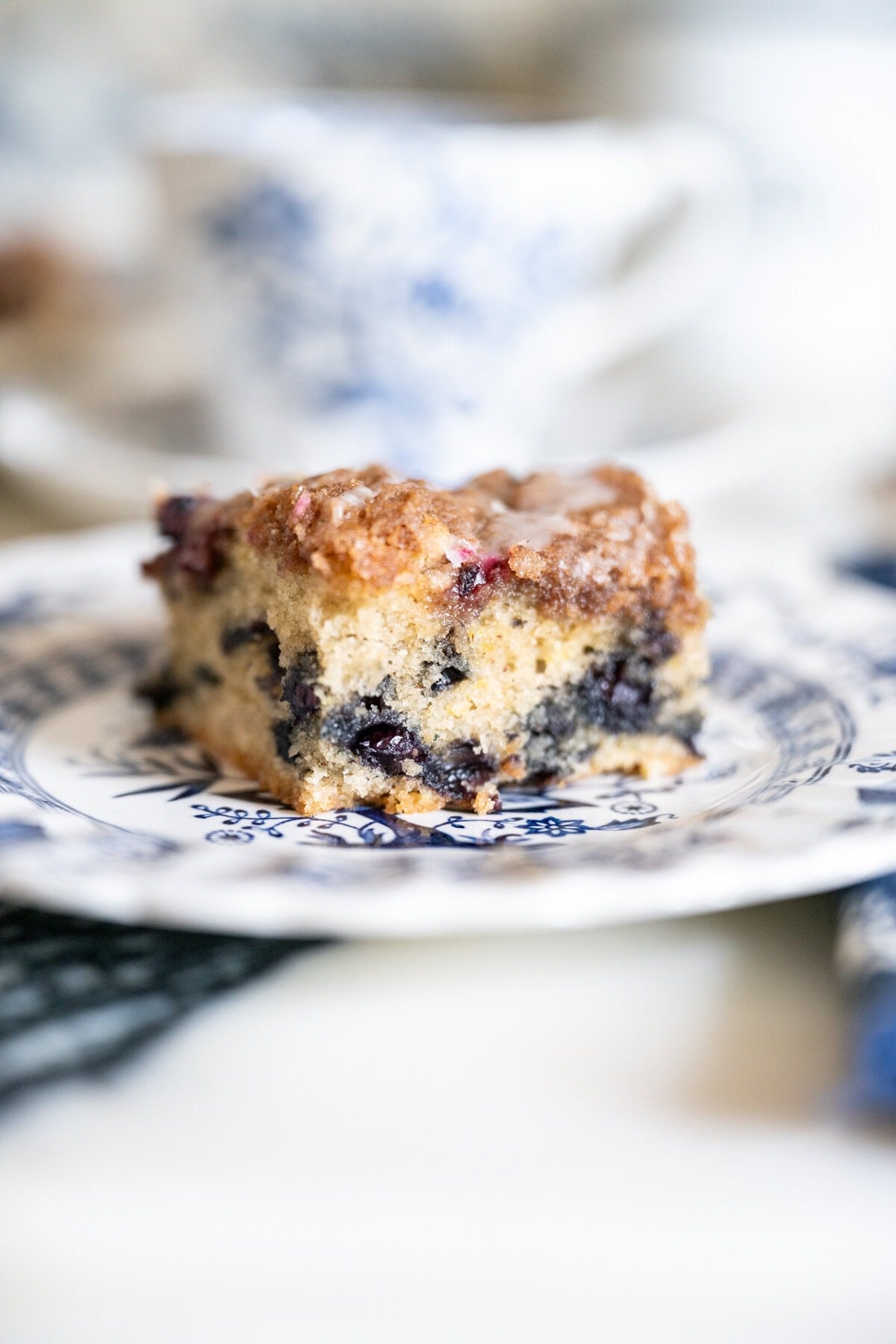Single slice of blueberry crumb cake showing a tender golden interior studded with blueberries beneath a thick crumb topping.